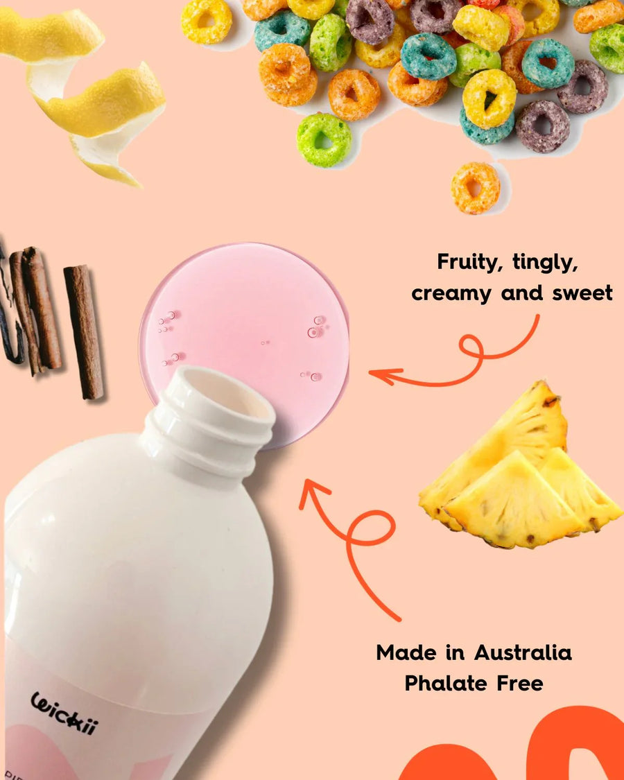 Fragrance oil bottle with pink liquid, fruit loops, pineapple, lemon peel, and cinnamon sticks on peach background.