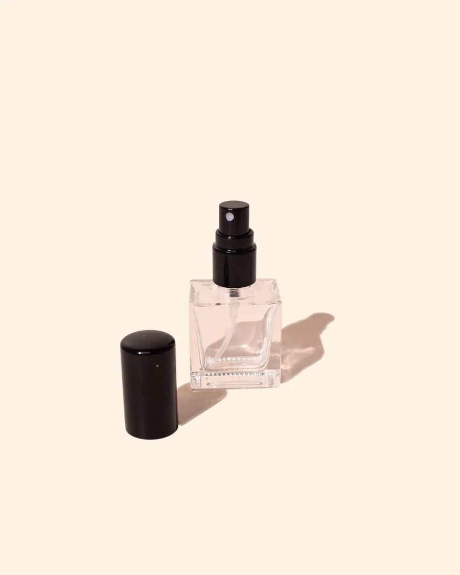 Clear 10ml perfume bottle with black atomiser and lid on a light background