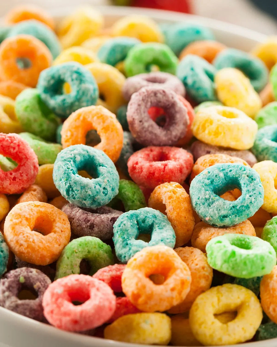 Colorful fruit loop cereal rings in a white bowl, close up view.