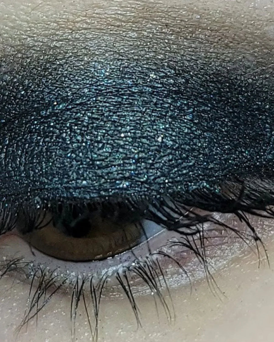 Closed eye with dramatic black glitter eyeshadow and visible lashes