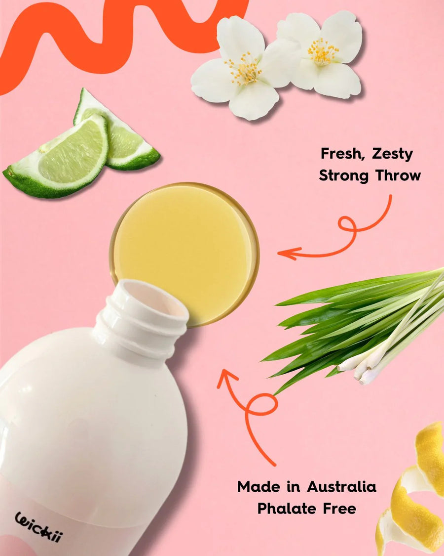 Fragrance oil bottle with lime, jasmine, lemongrass, and lemon peel on pink background.