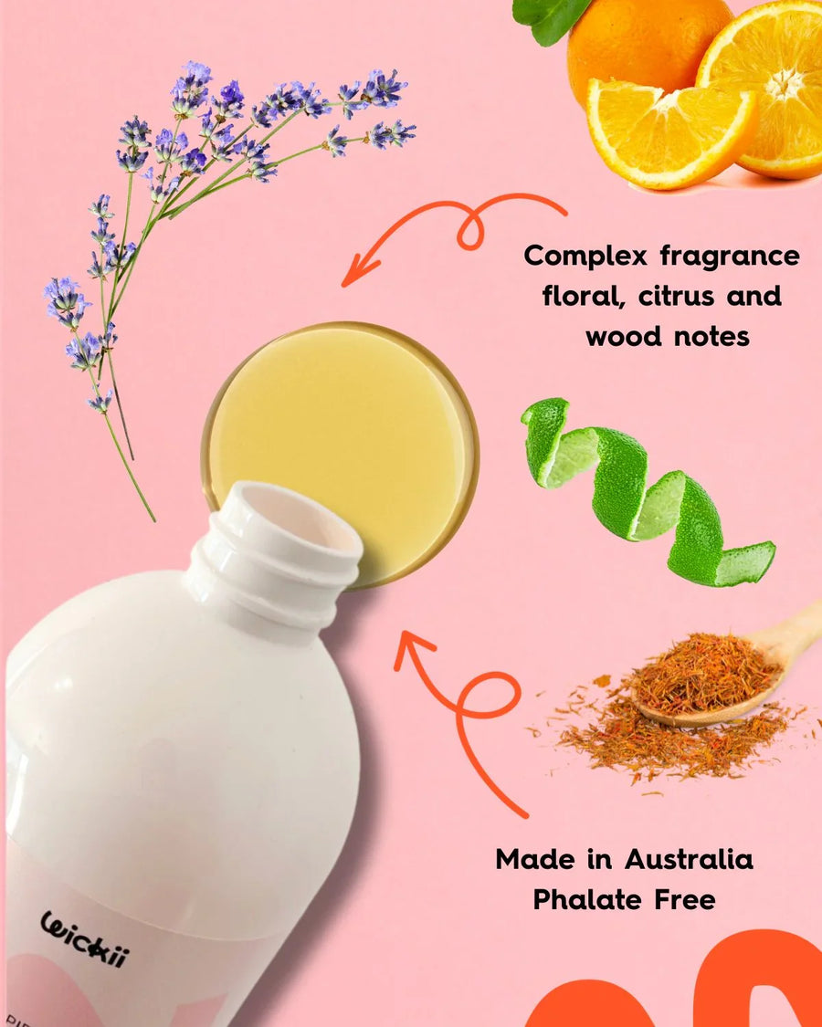 Fragrance oil bottle with floral, citrus, wood notes and ingredients on pink background