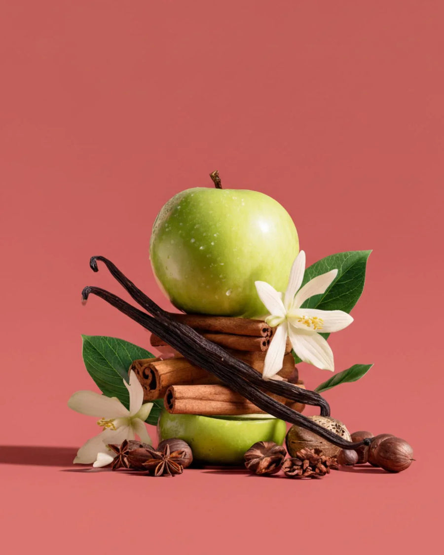 Green apple with cinnamon sticks, vanilla beans, star anise, nutmeg, and white flowers