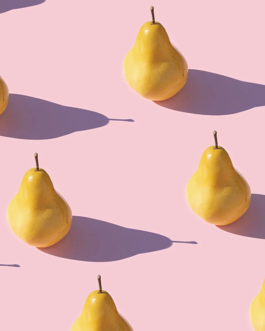 Yellow pears arranged on a pink background with long natural shadows, fruit photography