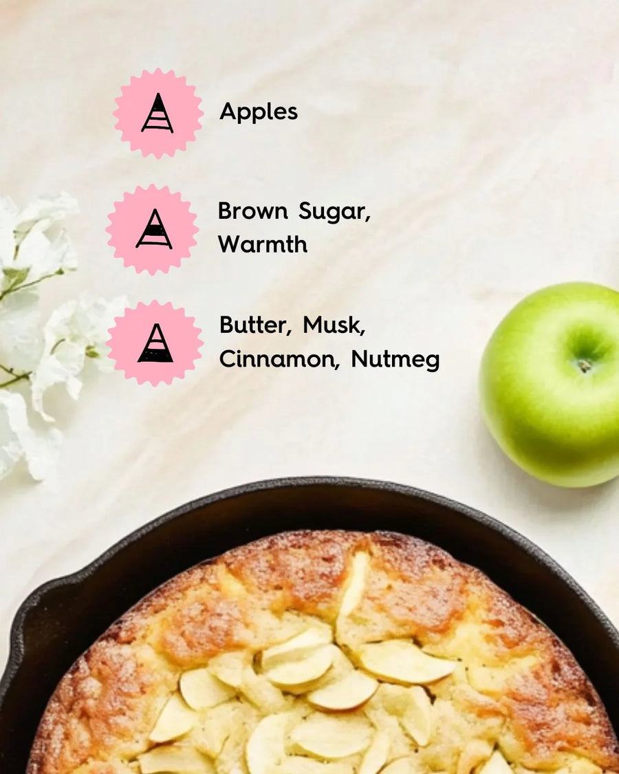 Apple cake in skillet with green apple, white flowers, and fragrance notes including apples, brown sugar, and spices.
