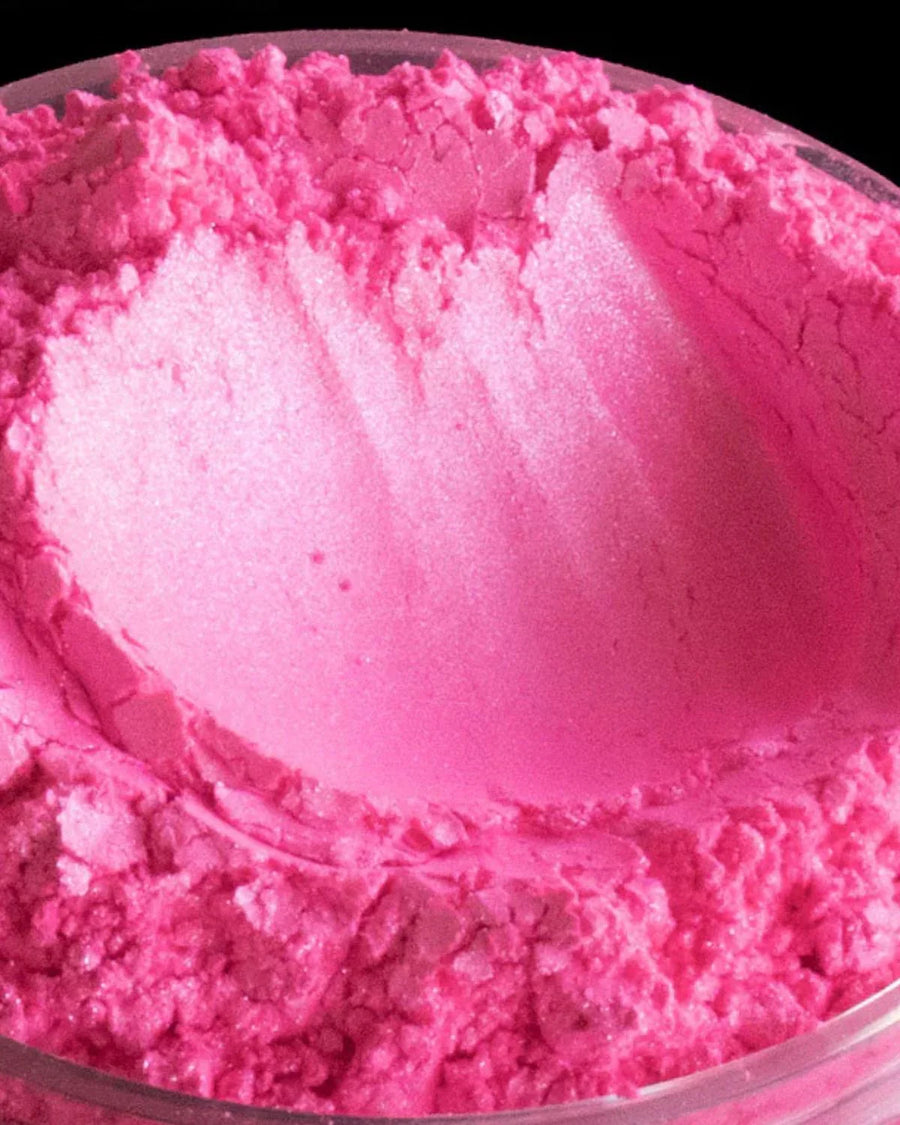 Bright pink mica powder for candle or soap making in a clear container, close up