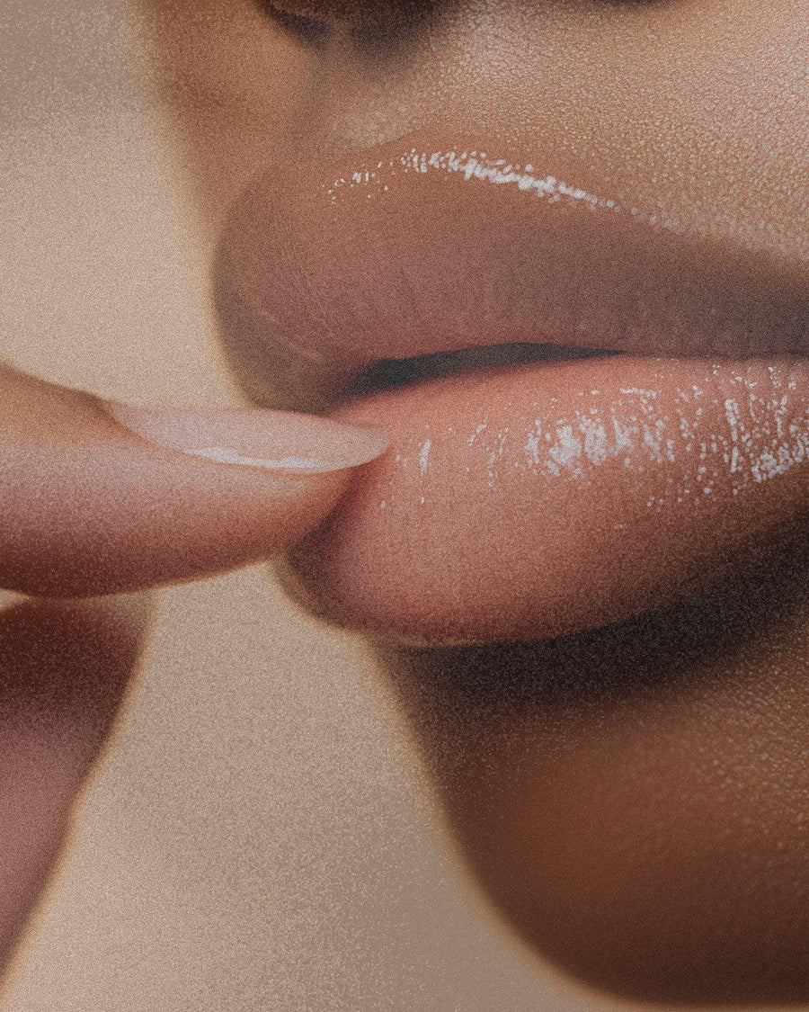 Close-up of glossy lips and finger, showcasing smooth, moisturized skin texture