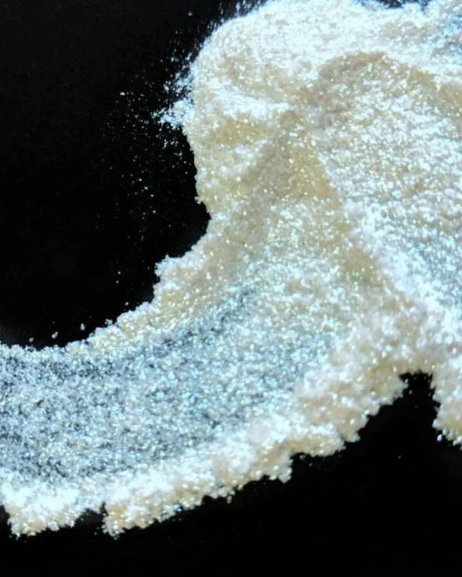 Iridescent mica powder scattered on a black surface for candle or soap making supplies.