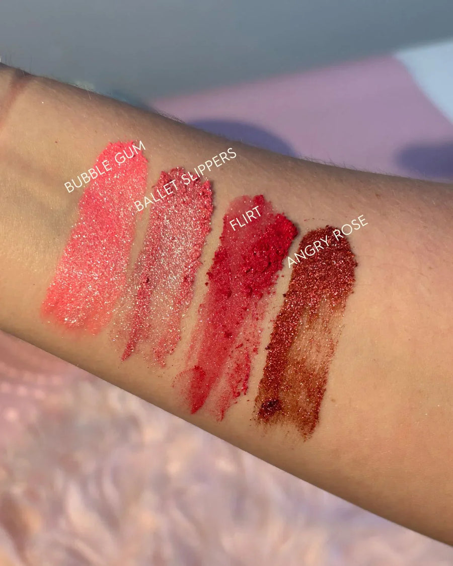 Four lipstick swatches on arm in pink and red shades labeled Bubble Gum, Ballet Slippers, Flirt, Angry Rose.