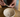 Hands mixing candle making wax in a ceramic bowl with a wooden spatula