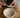 Hands mixing candle making wax in a ceramic bowl with a wooden spatula