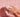 Hands washing with soap and foam in front of pink tiled bathroom wall