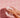 Hands washing with soap and foam in front of pink tiled bathroom wall