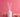 White reed diffuser bottle with reeds and dried flowers on pink background