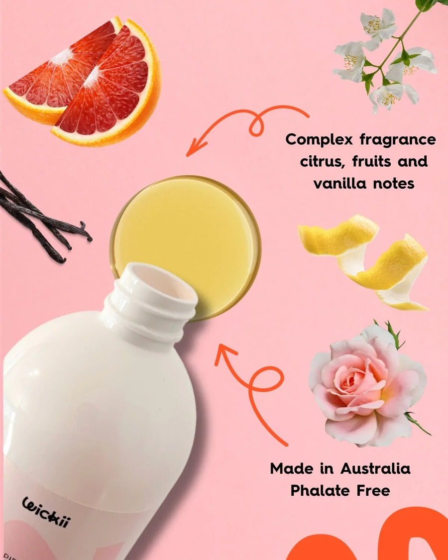 Fragrance oil bottle with citrus, vanilla, flowers and fruit on a pink background.