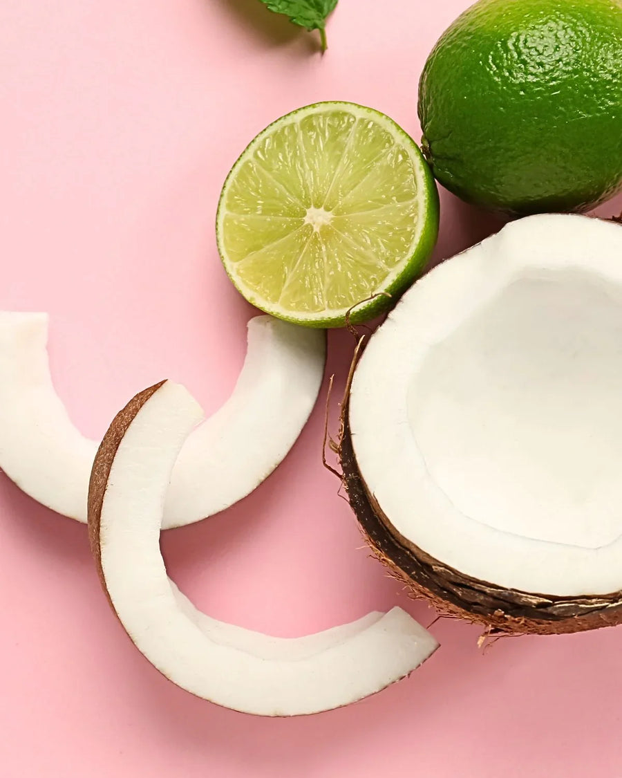 Fresh coconut slices and whole lime on pink background, fragrance oil inspiration