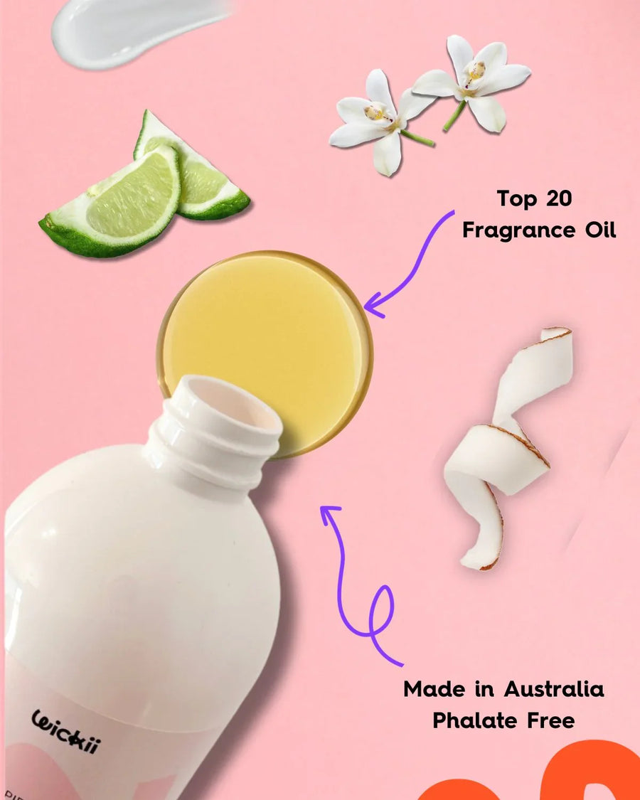 Fragrance oil bottle with spilled oil, lime slices, white flowers, and coconut on pink background