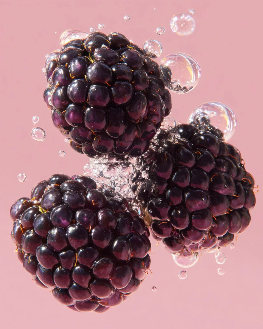 Fresh blackberries in sparkling water with bubbles on a pink background