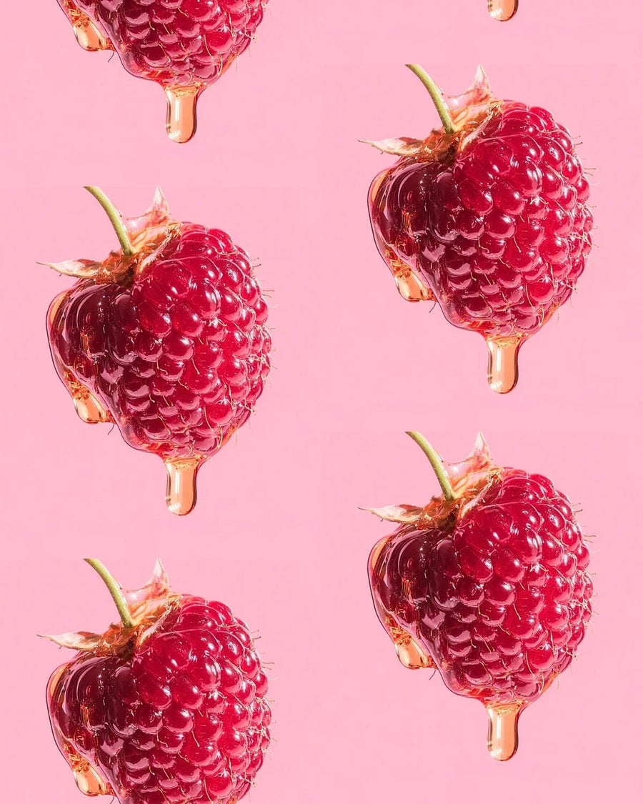 Juicy raspberries covered in golden syrup on a pink background, perfect for fragrance oils.
