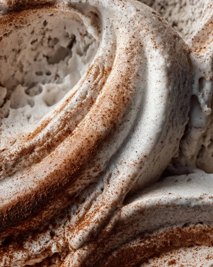 Close-up of creamy whipped soap base with brown cinnamon-like powder sprinkled on top