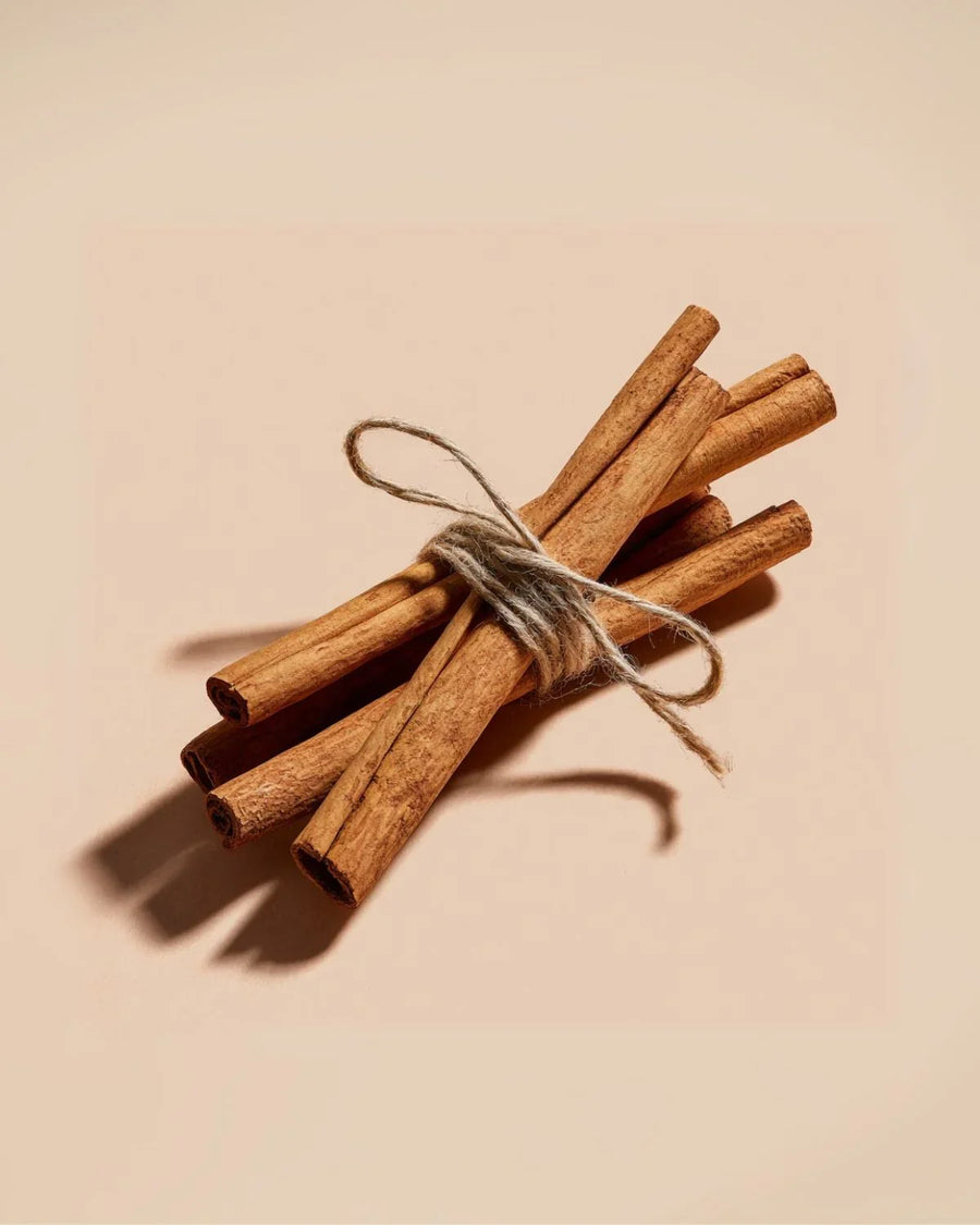 bundle of cinnamon sticks tied with twine on beige background