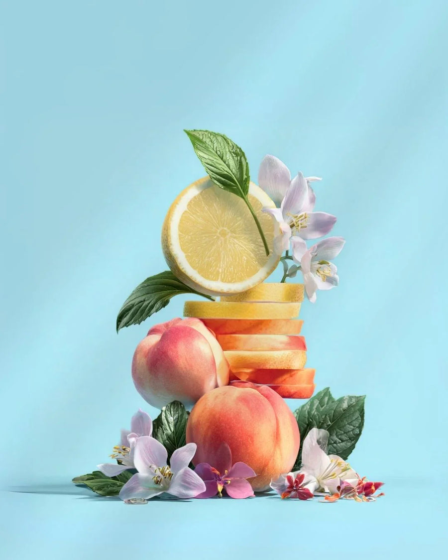 Fresh peaches, lemon slices, green leaves, and fragrant flowers on a pastel blue background.