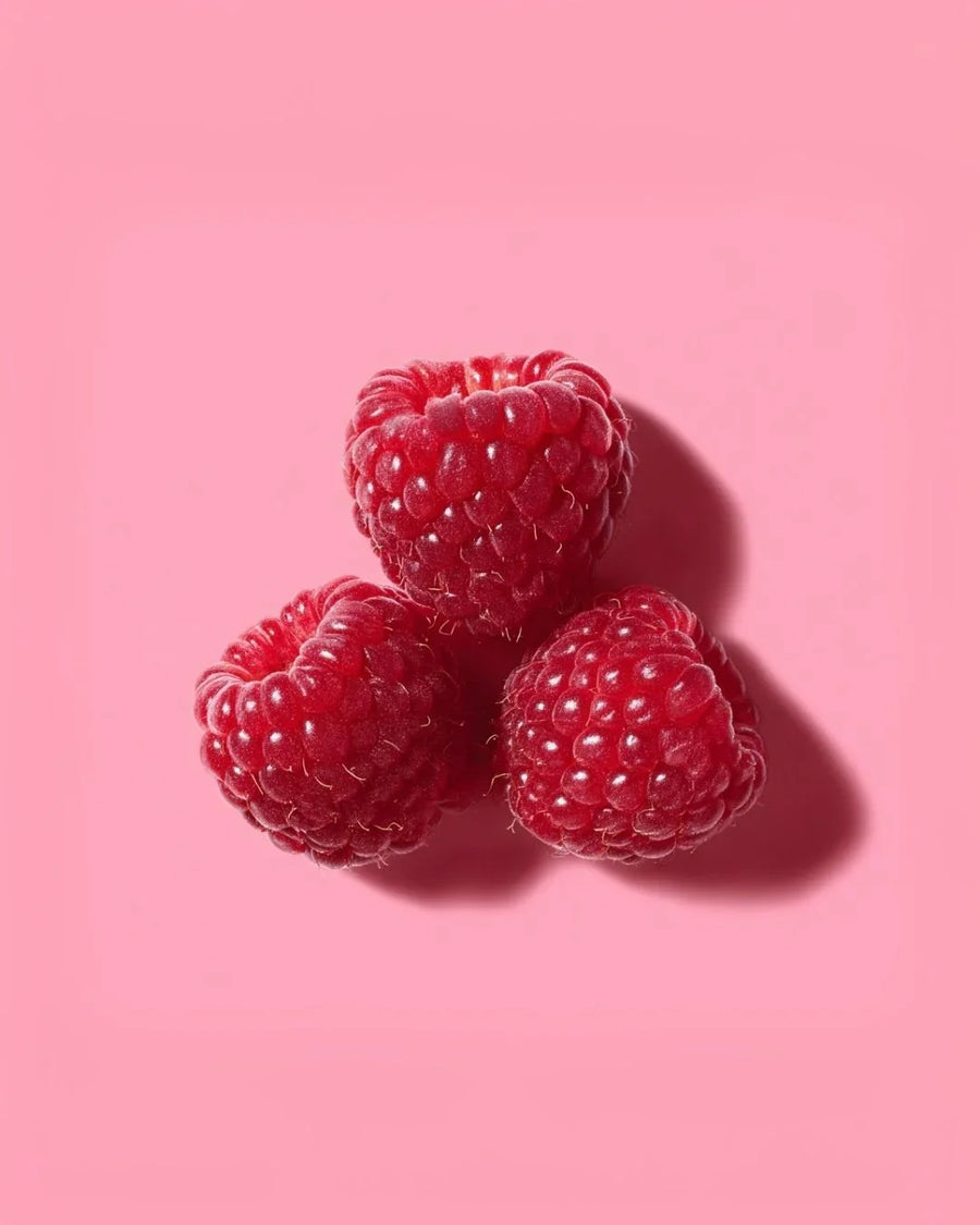 Three fresh raspberries on a pink background, ideal for fragrance oil or candle making supplies.