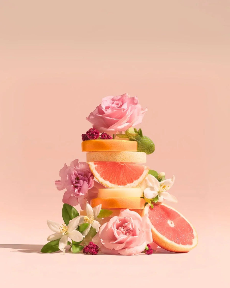 Stacked grapefruit slices with pink roses and white blossoms on a pastel background