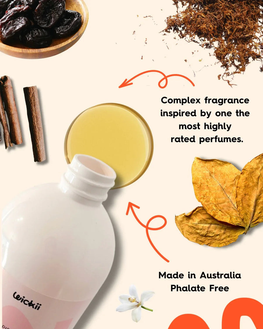 Candle fragrance oil bottle surrounded by cinnamon sticks, dried prunes, tobacco leaves, and white flower, labeled phthalate free and made in Australia.