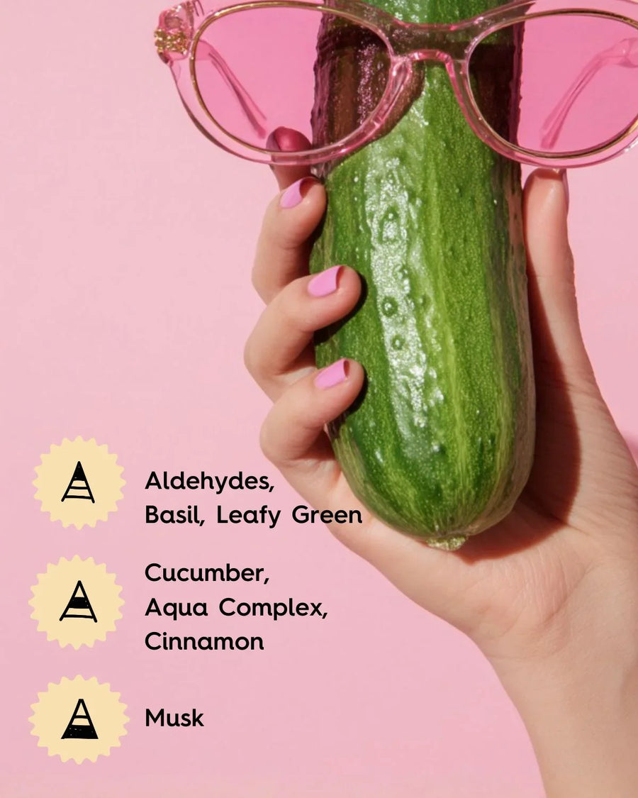 Hand holding a cucumber with pink sunglasses, fragrance oil notes listed on pink background