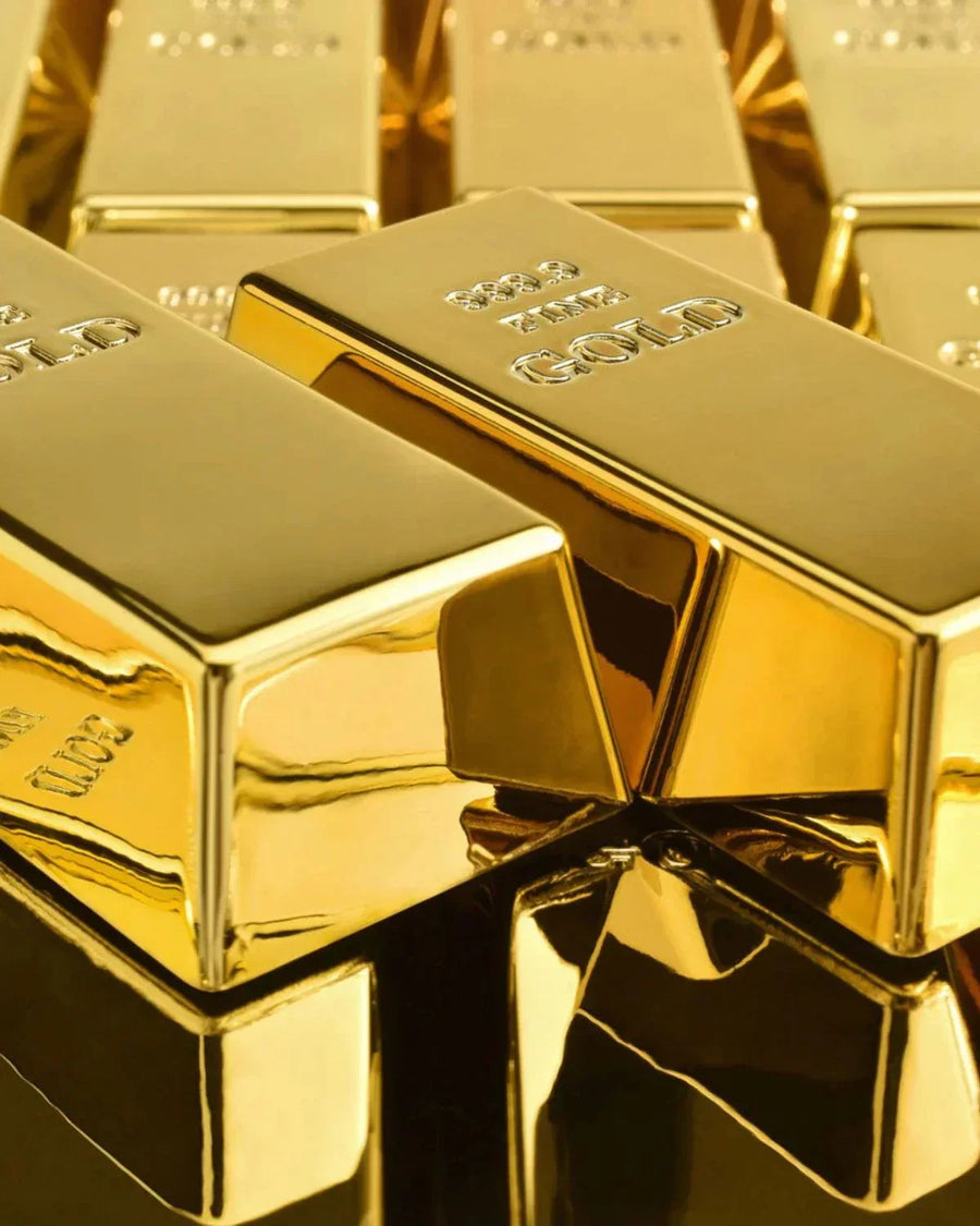Shiny gold bars stacked together, showing reflective metallic surfaces and embossed text.
