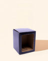 Purple candle box with clear front window on beige background, ideal for candle packaging.