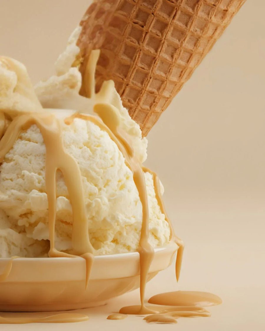Vanilla ice cream in bowl with caramel sauce and waffle cone on neutral background