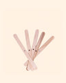 Wooden candle wick holders with holes, fanned out on a neutral background.