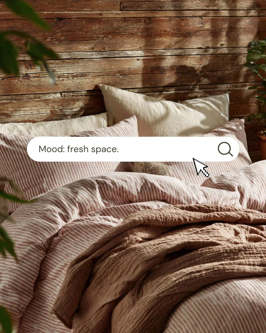 Cozy bed with striped linens, throw blanket, and wooden wall in a fresh, inviting bedroom.