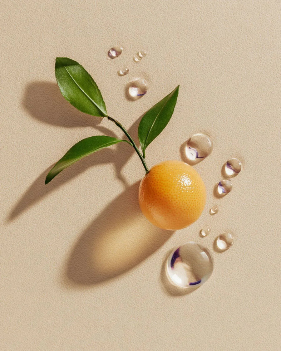 Fresh mandarin with green leaves and water droplets on a beige background, essential oil concept