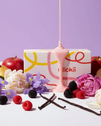 Assorted fruits, vanilla pods, and flowers with pink wax pour and a scented candle box
