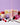 Assorted fruits, vanilla pods, and flowers with pink wax pour and a scented candle box