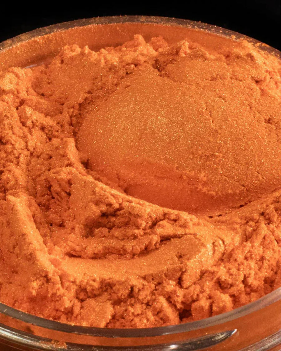Shimmering orange mica powder pigment in a clear container for candle and soap making