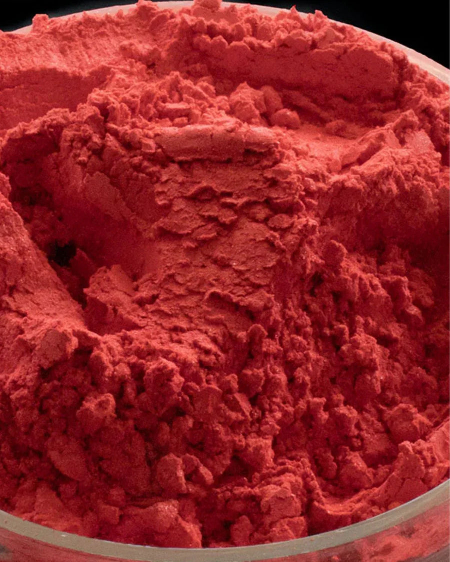 Close-up of vibrant red candle dye powder in a clear container, candle making supplies