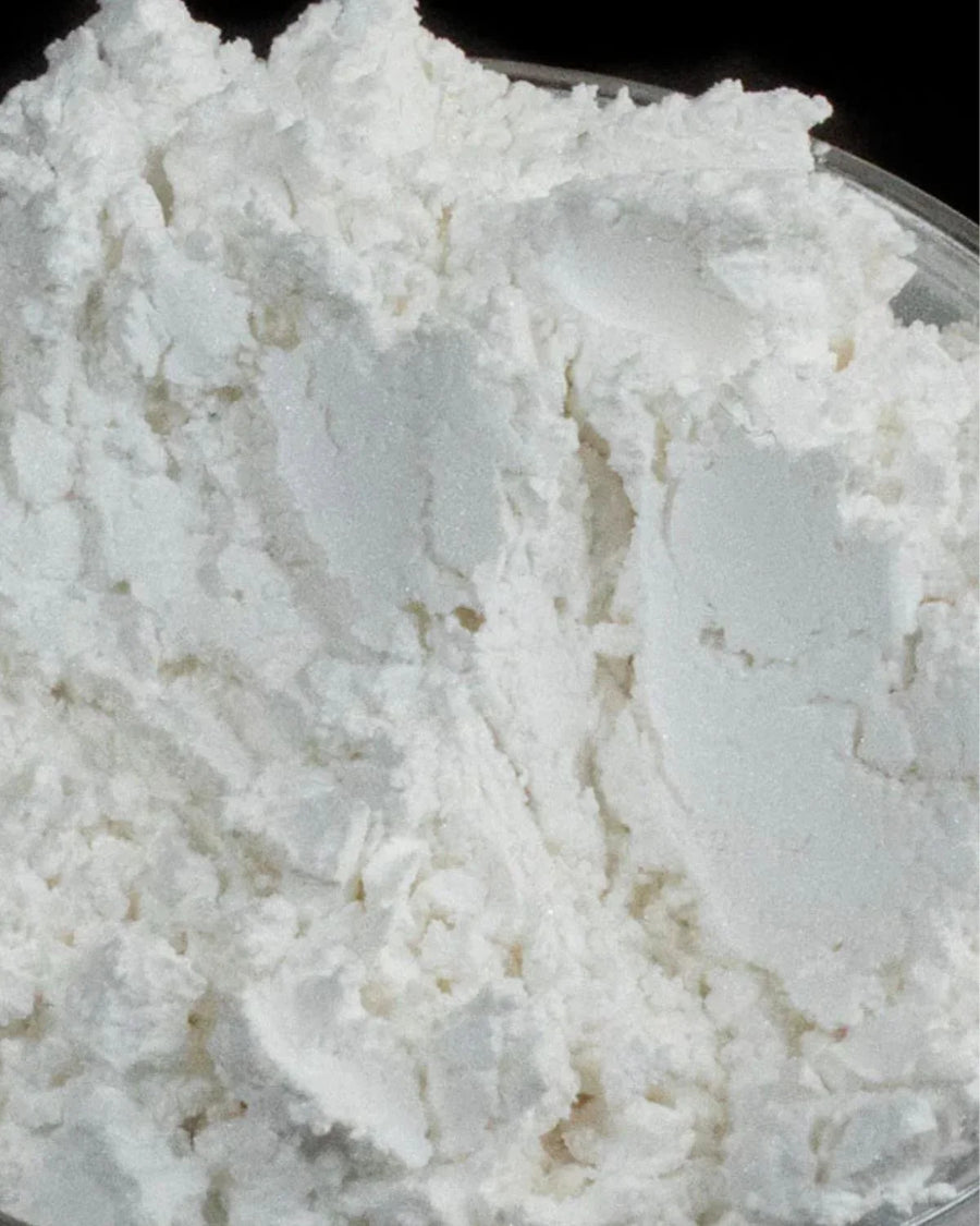 Close-up of a white powdered soap base in a glass container for candle and soap making supplies