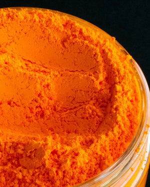 Bright orange pigment powder in a clear plastic jar for candle or soap making supplies