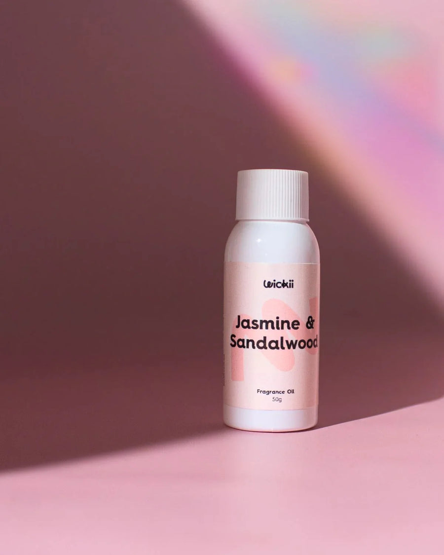 Jasmine and Sandalwood fragrance oil bottle on a pink surface with soft pastel background
