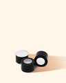 Black plastic screw caps for candle making containers on beige background