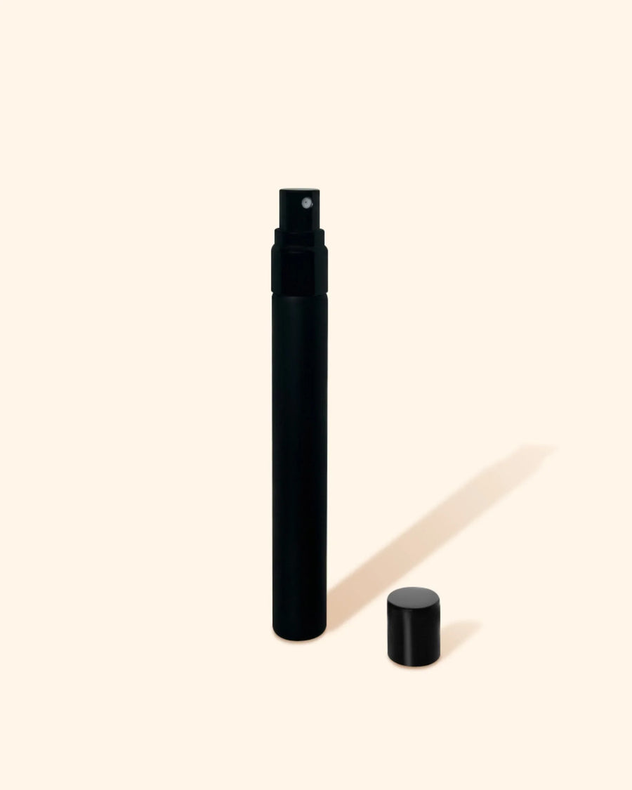 Black spray bottle for fragrance oils with cap on minimal beige background