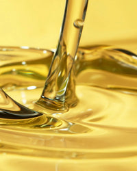 Closeup of golden fragrance oil being poured, ideal for candle and soap making supplies