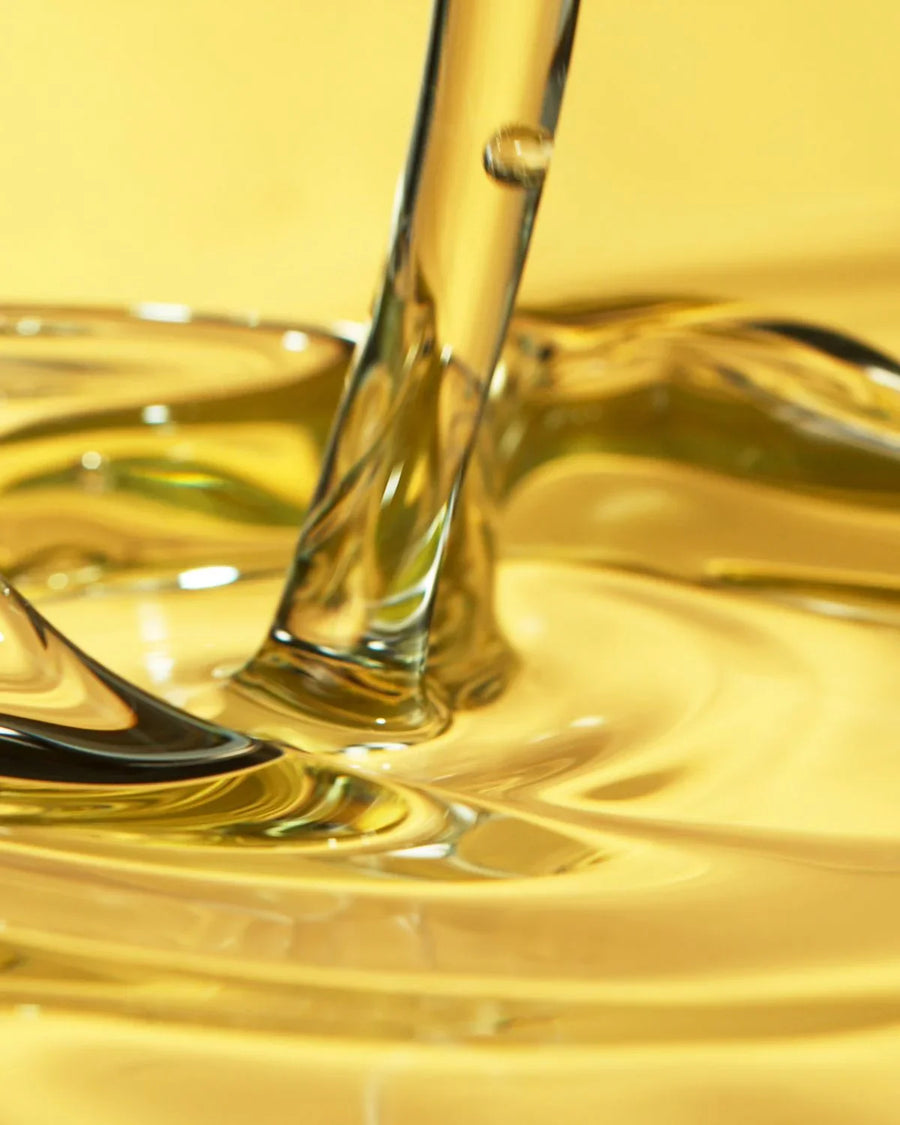 Closeup of golden fragrance oil being poured, ideal for candle and soap making supplies