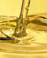 Closeup of golden fragrance oil being poured, ideal for candle and soap making supplies