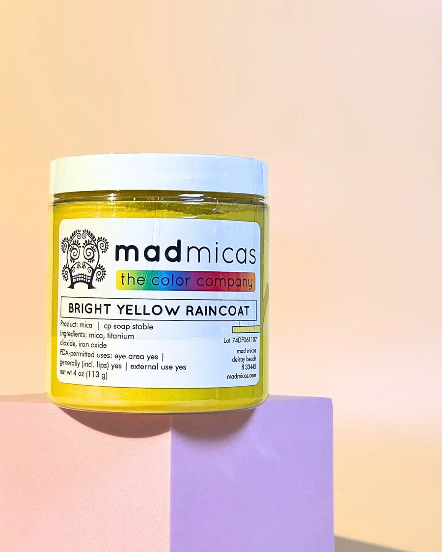 Bright yellow mica powder jar for soap and candle making on pastel blocks