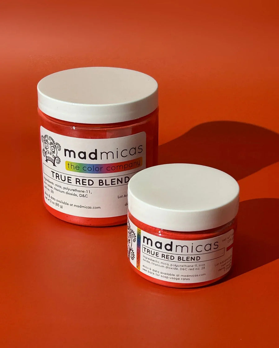 Two jars of Mad Micas True Red Blend mica powder on a red background, ideal for soap and candle making supplies.